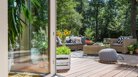 Schöne Terrasse mit gemütlichen Lounge-Möbeln, Teppich, Kissen und Blumen